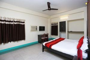 a bedroom with a bed and a ceiling fan at Hotel Penguin International in Kolkata