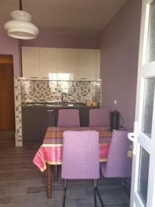 a kitchen with a table with purple chairs and a kitchen at Apartments Drago in Petrcane