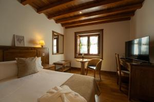 a bedroom with a bed and a desk and a television at Pazo Arretén in Padrón