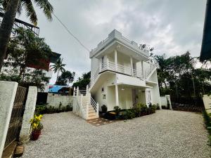 a white house with a balcony on top of it at Babuloos Homestay in Varkala