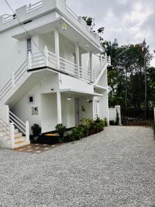 a white house with a balcony and a driveway at Babuloos Homestay in Varkala +7 photos