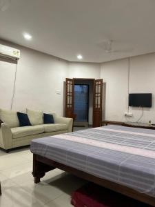 a bedroom with a bed and a couch and a tv at AAC in Chennai