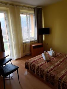 a bedroom with a bed and a chair and two windows at KORONA Sanatorium Uzdrowiskowe in Muszyna