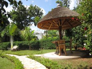 a table and chairs under a umbrella in a garden at Precious Guesthouse in Entebbe