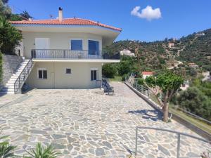 a house on a hill with a stone patio at Aegean Beachfront Apartments in Petriaí