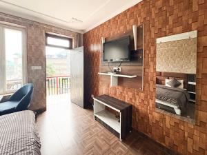 a bedroom with a bed and a tv on a brick wall at Young Monk Hostel Bhagsu,Mcleodganj in Dharamshala
