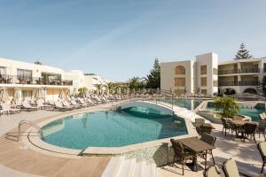 a large swimming pool with chairs and tables in a resort at Vantaris Palace in Georgioupolis
