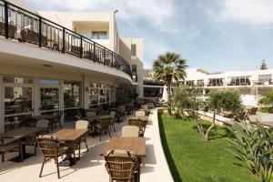 an outdoor patio of a hotel with tables and chairs at Vantaris Palace in Georgioupolis