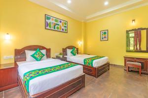 two beds in a yellow room with a piano at Treebo Kaler Hotel & Resorts in Nainital
