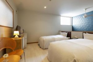 ein Hotelzimmer mit zwei Betten und einem Fernseher in der Unterkunft Shushu in Asago
