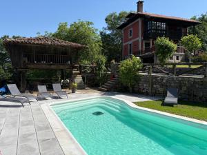 a pool with chairs and a house in the background at Casa Escuela de Torín - La Casona de Torin in Torín