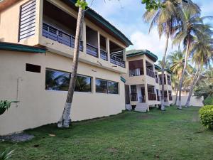 a building with palm trees in front of it at Hotel Palm Rock Beach in San-Pédro