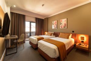 a hotel room with two beds and a television at Made Inn Entroncamento in Entroncamento