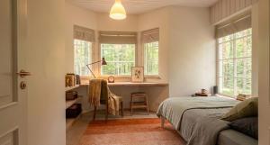 a bedroom with a bed and a desk and windows at Meremaa Ateljee in Salinõmme