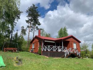 a small red house in a field with a tree at Amaleczka Woda Las in Podjazdy