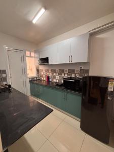 a kitchen with green cabinets and a black counter top at Pool View 3 BR Adora, Goa Amoret Homes in Chicalim