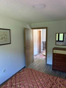 a bedroom with a bed and a dresser and a door at Holiday House Ostrozac na Uni in Ostrožac