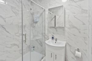 a white bathroom with a shower and a sink at Nile - Cosy Studio Apartment by Traboule Properties Ltd in Warrington
