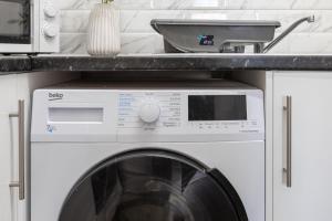 a washing machine in a kitchen under a counter at Nile - Cosy Studio Apartment by Traboule Properties Ltd in Warrington