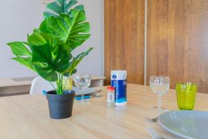 a table with a potted plant and glasses on it at Appart-Hotel du drapeau bleu Residence Kiwi in Aytré