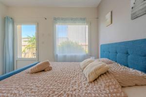 a bedroom with a bed with a blue headboard and two windows at Appart-Hotel du drapeau bleu Residence Kiwi in Aytré