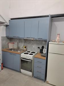 a kitchen with blue cabinets and a stove and a refrigerator at Patasa holiday apartment in Pyrgi