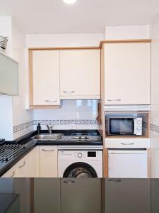 a kitchen with white cabinets and a sink and a microwave at Bella Vista in Portosin