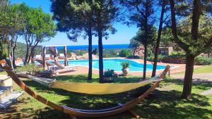 a hammock in a yard with a swimming pool at Villa Esmerea Portocervo con Piscina privata ,Jacuzi e Sauna in Porto Cervo