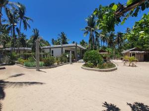 a building on a sandy beach with palm trees at Pili Beach Resort Agmanic in Santa Fe