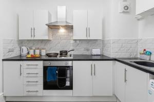 a kitchen with white cabinets and a black oven at Tigris - Cosy Studio Apartment by Traboule Properties Ltd in Warrington +20 photos