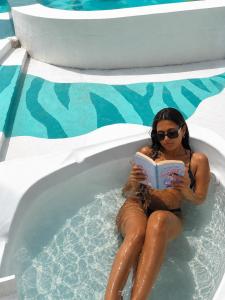 a woman sitting in a swimming pool reading a book at Epic Wild Wilpattu in Nochchiyagama