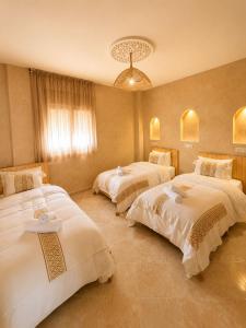 a bedroom with three beds and a chandelier at Yara Lodge in Tamraght Ou Fella