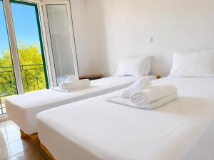 two white beds in a room with a large window at Olga Apartments in Kolónion