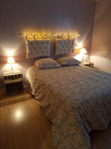 a bedroom with a large bed with two lights on it at Chambre d'Hôtes Les Bruyères in Cadouin