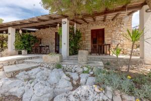 a stone house with a patio and a table at Borgo del Sole Salento in Torre Vado