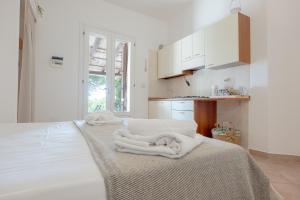 a white kitchen with white towels on a bed at Borgo del Sole Salento in Torre Vado