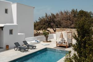 a patio with a swimming pool and chairs and a house at Ammolofos Luxury Apartment & suites in Naxos Chora