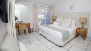 a bedroom with a large white bed and a desk at D3 Sea Lodge - by Stay in Umhlanga in Durban