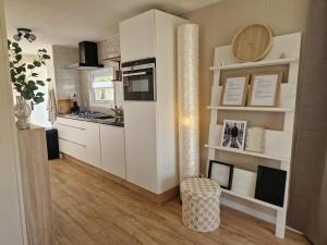 a kitchen with white cabinets and a stove top oven at Chalet in Berkhout, close to the beach in Berkhout +20 photos