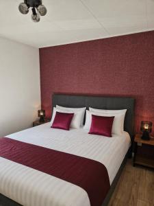 a bedroom with a large bed with two red pillows at Chalet in Berkhout, close to the beach in Berkhout