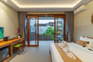 a bedroom with a bed and a desk and a television at Pondok Tis Bisma in Ubud