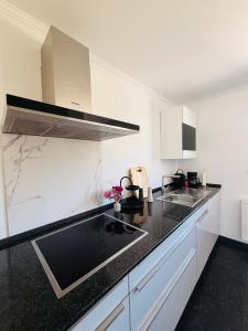 a kitchen with white cabinets and black counter tops at Ferienwohnung Auszeit Langsur in Langsur