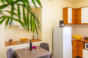 a kitchen with a table and a white refrigerator at Apartments & Rooms Sanja in Rab