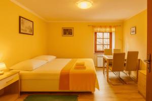 a yellow bedroom with a bed and a table at Domačija Harmonija in Vremski Britof