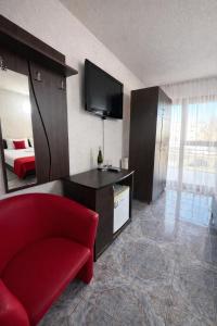 a living room with a red chair and a television at Vila Rubin in Eforie Nord