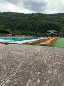 a large swimming pool with benches and a building at Садиба Тушер in Rakhiv
