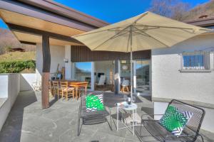 a patio with a table and chairs and an umbrella at La Cà Da Brè - Garden House with Views - Happy Rentals in Lugano