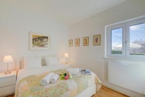a white bedroom with a bed and a window at La Cà Da Brè - Garden House with Views - Happy Rentals in Lugano