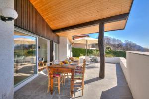 a patio with a wooden table with chairs and umbrella at La Cà Da Brè - Garden House with Views - Happy Rentals in Lugano