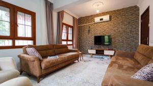 a living room with two couches and a brick wall at Flower Apart 2 - Flower Hotel Patara in Gelemiş